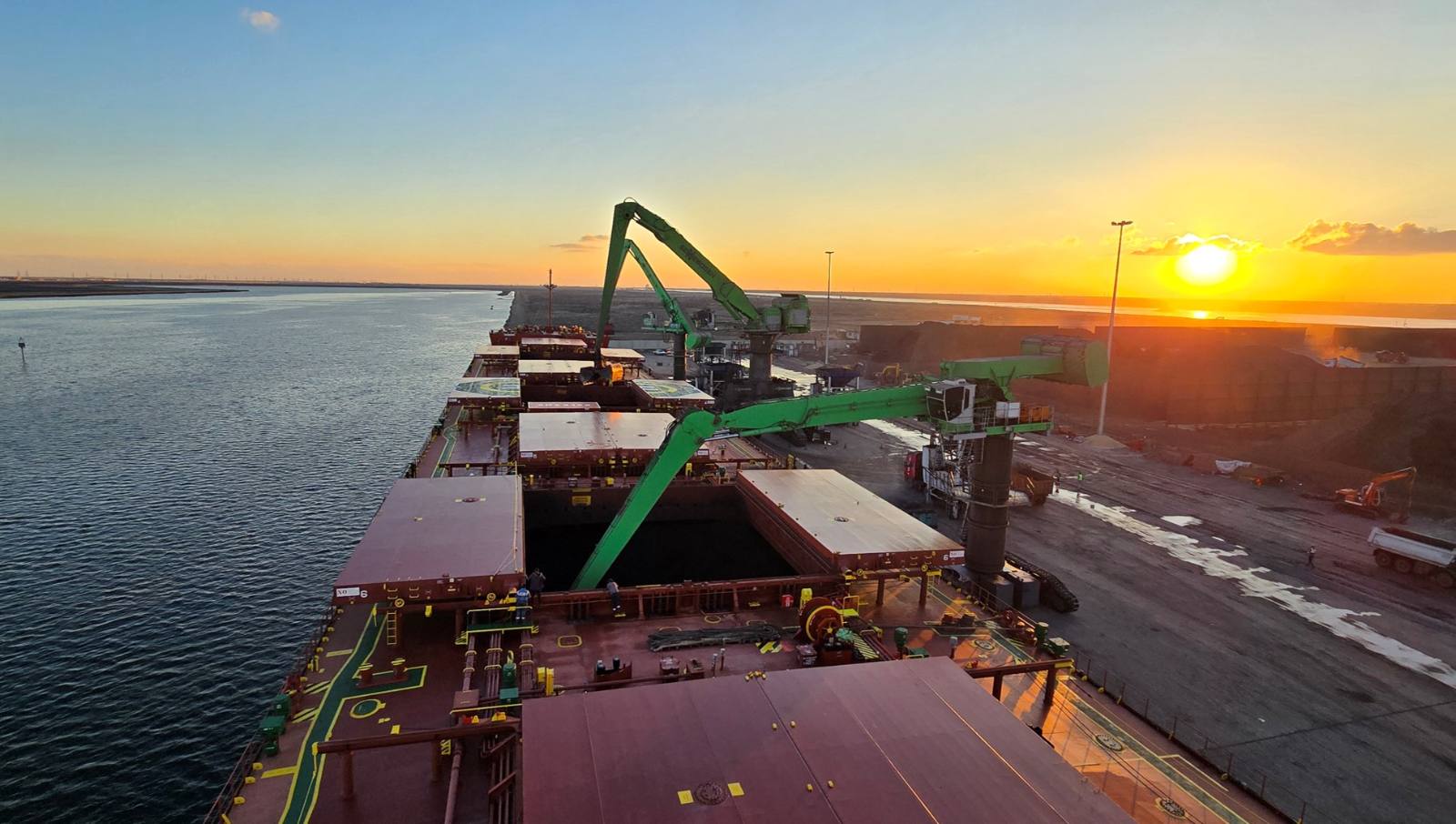 Sennebogen cranes discharging a bulk carrier at sunset